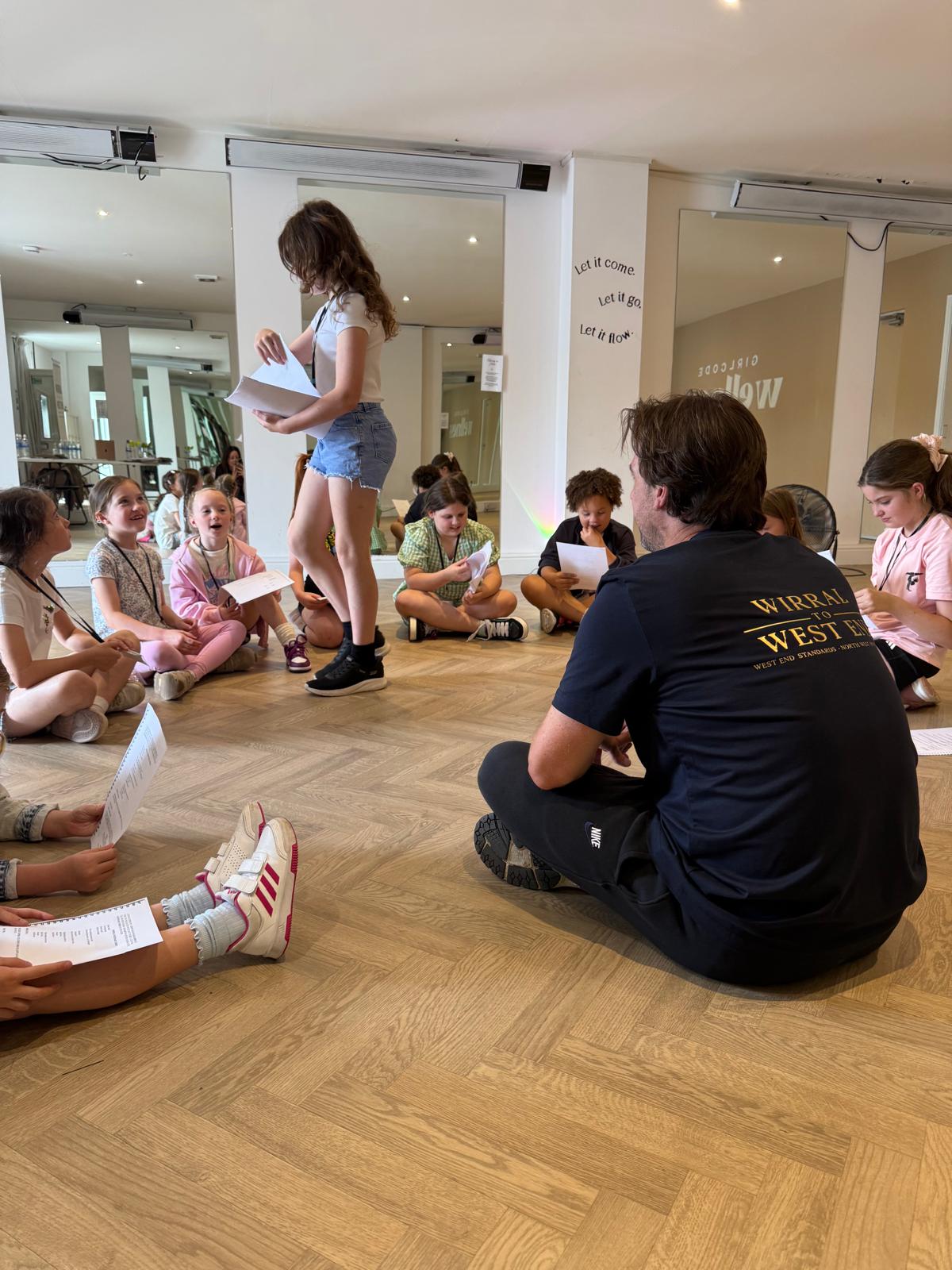 A workshop leader listening as a young performer works with a script